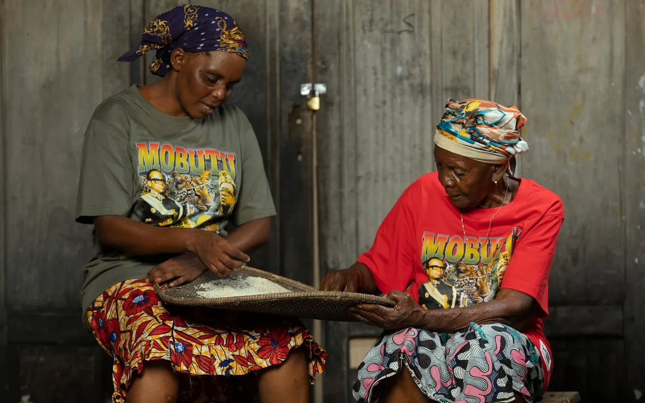 Deux mamans trient le riz en t-shirts Mobutu Zaïre vert et rouge