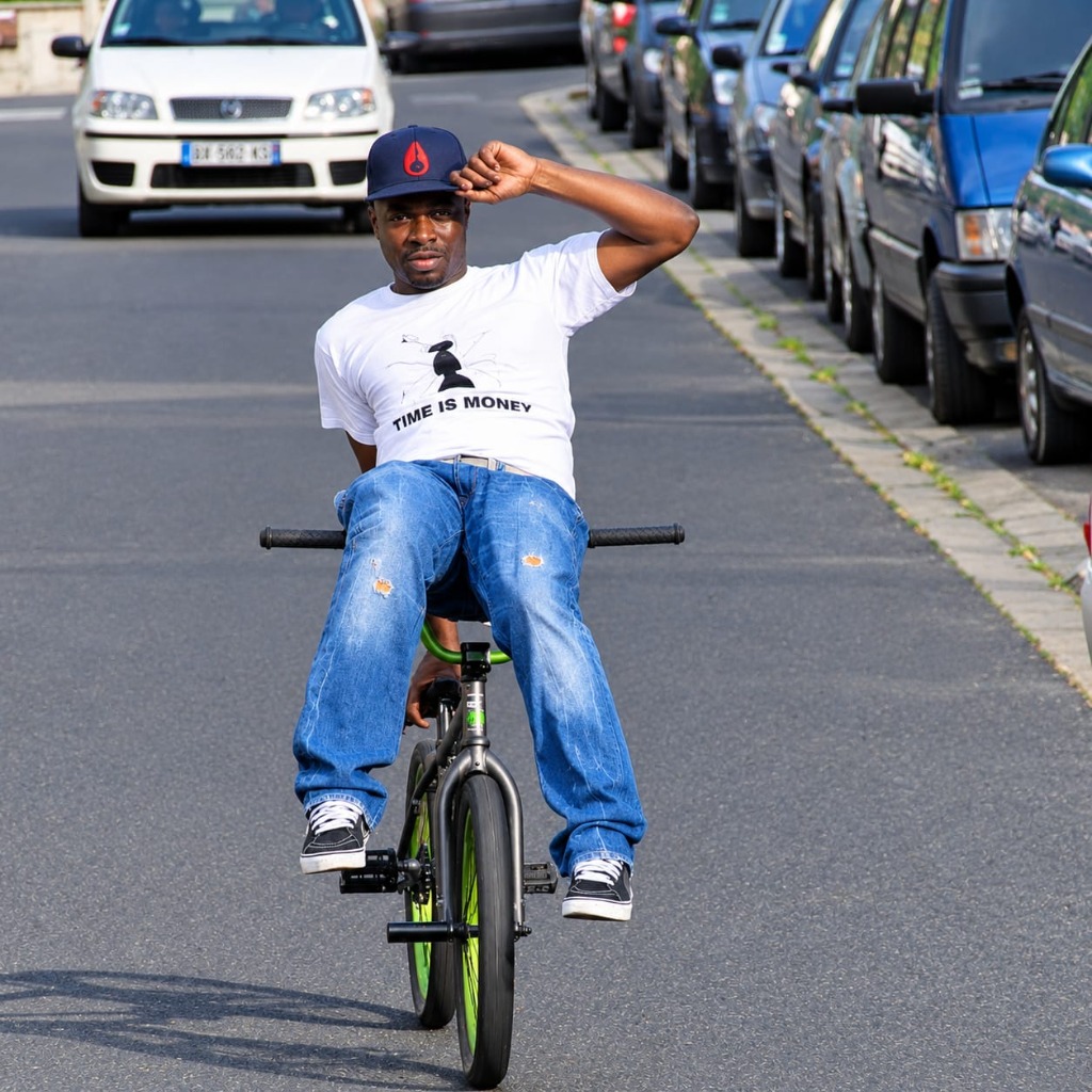 Luyindula Kongolo, fondateur de Match Kwata en t-shirt Time Is Money sur son BMX